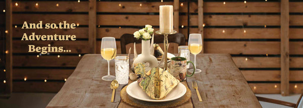 A table setting for a weeding. The tablescape features a Montana Kitchen towel folded into a napkin. The table also features a Montana coffee mug, wine glasses, candle, flowers, and a deer antler for the table setting.