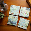 Glacier National Park Natural Stone Coaster Set by Xplorer Maps comes in a set of four making up the map of Montana. The coasters are sitting on a tile table with a cactus and candle. Features places in the park such as Logan Pass, Lake McDonald Lodge, Many Glacier Lodge, Two Medicine, Glacier Park Lodge, and the Going-to-the-sun Road. Flora and fauna include grizzly bears, elk, moose, mountain goats, and mountain lions.