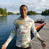 Person wearing a '1000 Islands' themed shirt by a lake with a boat and dock in the background.
