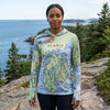 Person wearing a sun shirt hoodie with Acadia National Park design in a scenic outdoor setting.