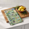 Wooden cutting board with a map design and a bowl of lemons on a kitchen counter.