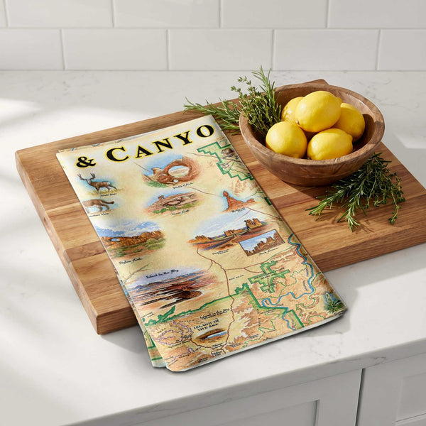 Map-themed towel on a wooden cutting board with lemons and herbs on a kitchen counter.