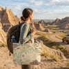 Person with a backpack and map bag in a desert landscape