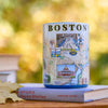 Mug with Boston design on top of a book against a blurred autumn background