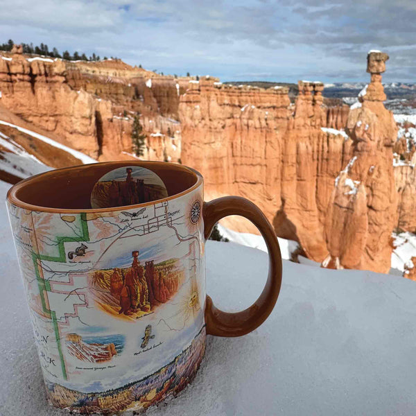 Orange 16 oz Bryce Canyon National Park Map Ceramic Mug amidst snow, showcasing canyons, hoodoos, horseback, Rim Trail, Sunrise Point, Sunset Point, Inspiration Point, Bryce Point.