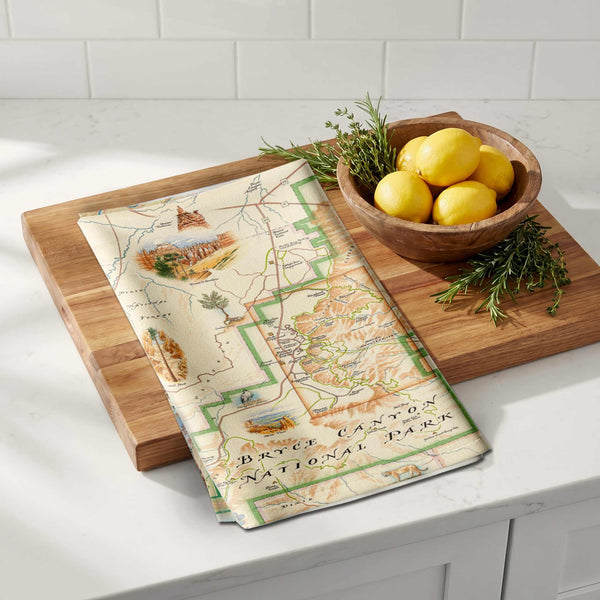 Map-themed kitchen towel on a wooden cutting board with lemons and herbs.