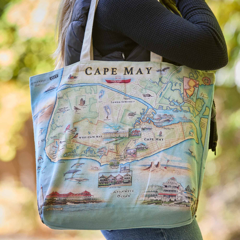 Tote bag with a map design of Cape May held by a person outdoors.