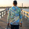 Person wearing a map-themed hoodie on a pier with fishing equipment.