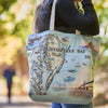Tote bag with a map of Chesapeake Bay design held by a person outdoors.
