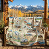 Colorado Map-themed blanket draped over a chair on a wooden deck with mountains in the background