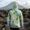 Person wearing a colorful hoodie with nature-themed designs standing on a volcanic landscape.