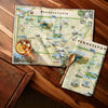 Pennsylvania-themed kitchen towel on a wooden surface with a drink.