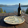 Wine bottle and glasses on a scenic lakeside table with a Flathead Lake map serving tray.