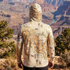 Person wearing a hoodie with a map design standing in front of a canyon landscape