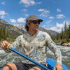 Man paddling a kayak in a mountainous area wearing a Grand Teton National Park sunshirt.