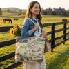 Woman holding a tote bag with Kentucky map design in a rural setting