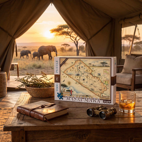 A 1000-piece jigsaw puzzle box labeled 'MASAT MARA PUZZLE' sits on a rustic wooden table inside a safari-themed tent. The background shows a warm sunset over an African savanna with elephants, while the table also holds a leather journal, brass binoculars, and a glass of amber liquid.