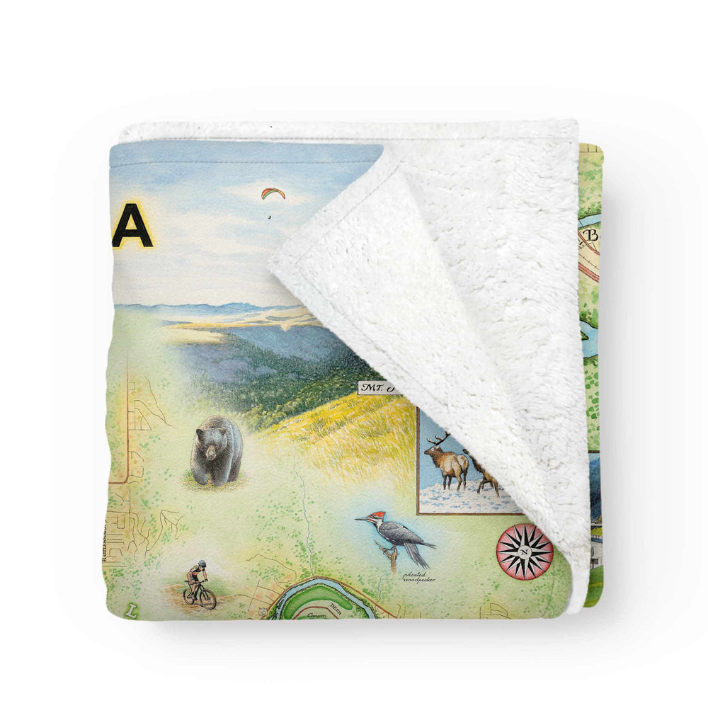 Missoula map fleece blanket featuring hand-drawn artwork by Xplorer Maps, folded to reveal soft white fleece lining in the top corner.