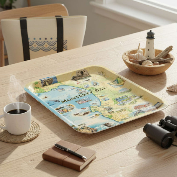 Monterey Bay  tray with a map design on a wooden table with a cup of coffee, notebook, and binoculars.