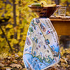 Map-themed towel draped over a bowl on a table with a blurred autumn background