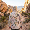 Person wearing a sun shirt hoodie with a Red Rock canyon map design in a desert landscape