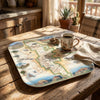 Map tray with a scenic design on a wooden table with a mug and newspaper.