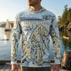 Person wearing a hoodie with a map of the San Juan Islands design, standing by a body of water with a sailboat and kayaker.