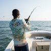 Man fishing on a boat with a colorful shirt and sunglasses, wearing a Sanibel & Captiva Islands sun shirt
