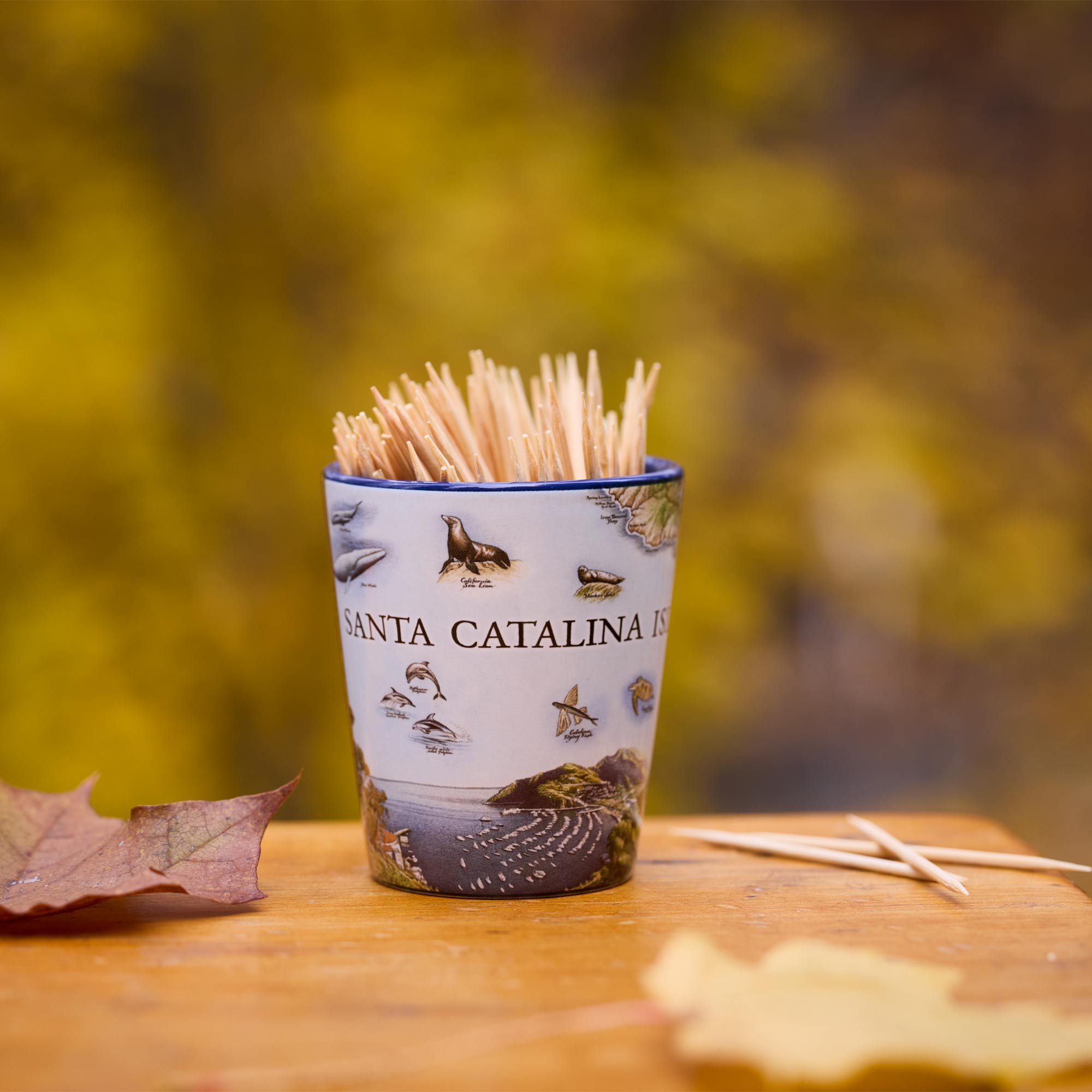 Shot glass with toothpicks on a wooden surface with a blurred natural background