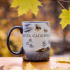 Mug with 'Santa Catalina' design on a wooden surface with autumn leaves.