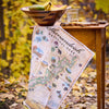 Map of Shenandoah National Park on a wooden table with a bowl and glass in an autumn setting.