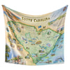 South Carolina Map Fleece Blanket hanging to showcase the full hand-drawn map design, featuring iconic landmarks and natural scenery.