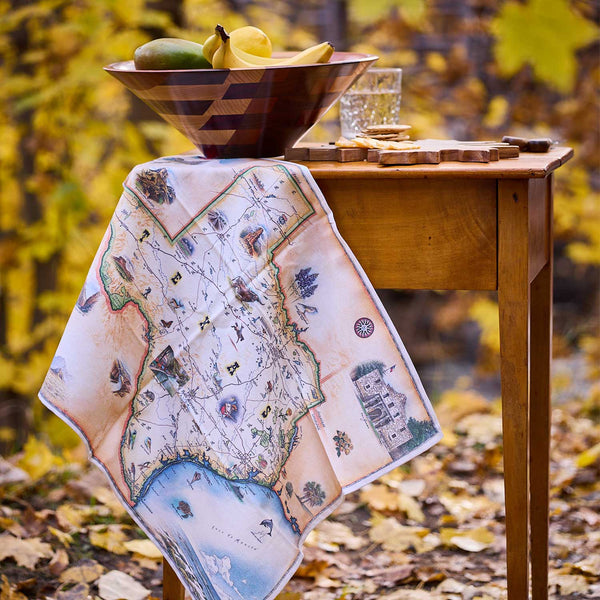 Map-themed tablecloth on a wooden table with autumn leaves in the background