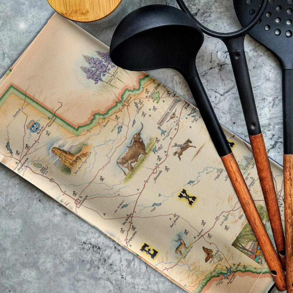 Texas kitchen towel laying on a counter top with ladles and kitchen utensils on top. 