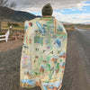 A man wearing Utah State Map fleece blanket around him. Featuring intricate details of popular cities, iconic landmarks such as Arches National Park and Bryce Canyon, and vibrant flora and fauna indigenous to the region.