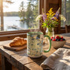 Mug with a scenic design on a wooden table with a view of a lake.