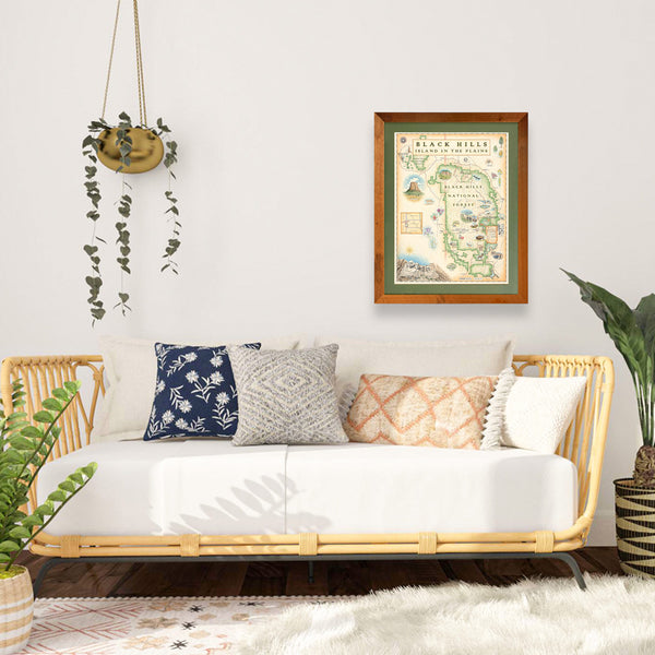 Black Hills National Forest hand-drawn map in a Montana Flathead Lake reclaimed larch wood frame and green mat hanging over a day bed with plants on both sides. 